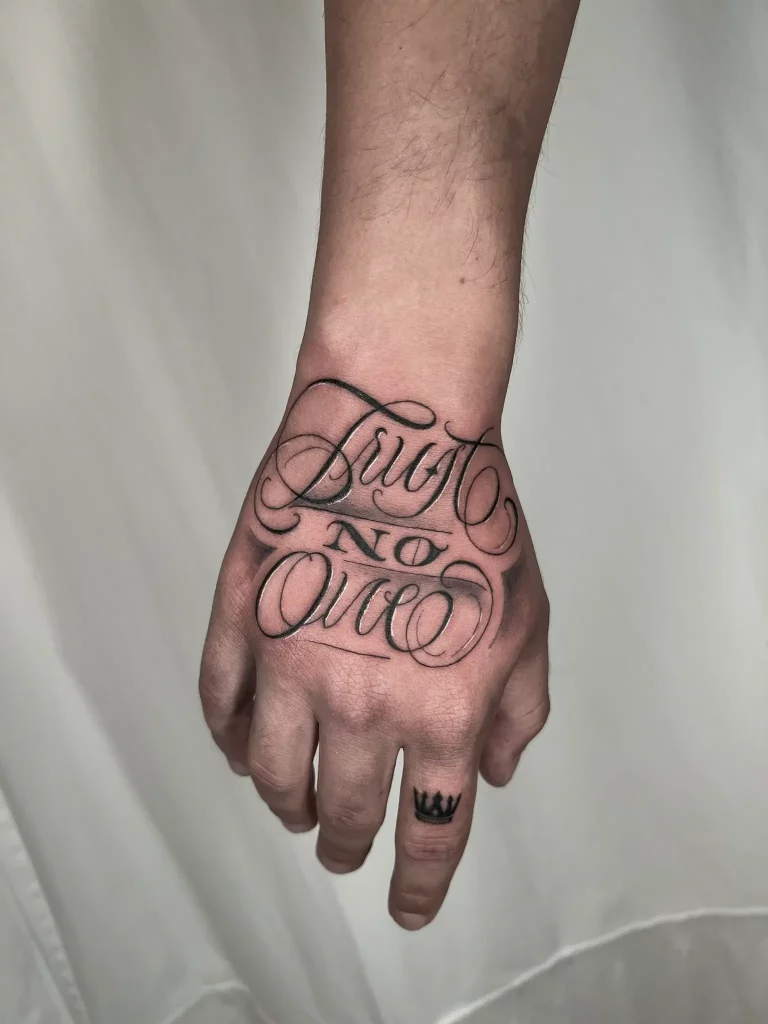 Tattoo auf dem Handrücken, dass einen Lettering Schriftzug zeigt