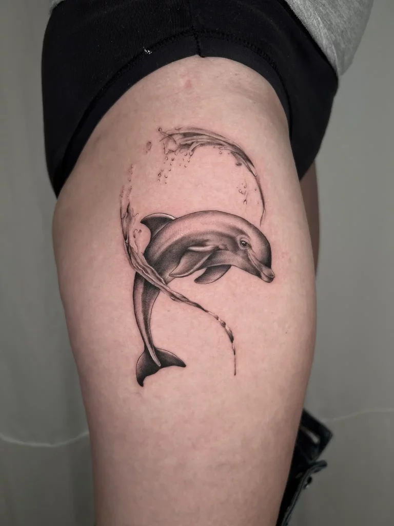Tattoo auf dem Oberschenkel, dass einen Springenden Delfin zeigt