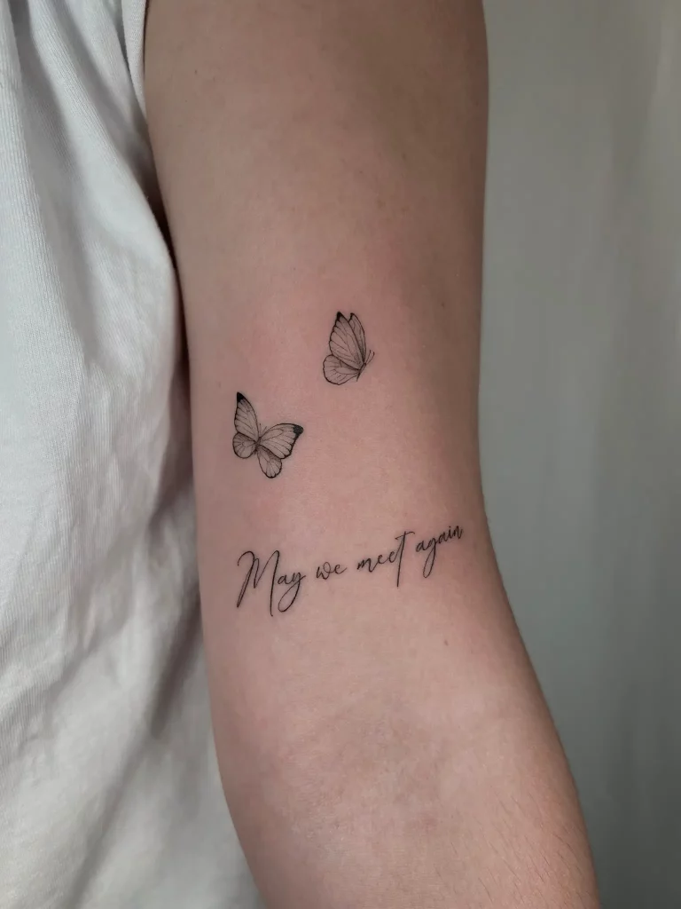 Tattoo in der Ellenbeuge, dass zwei Schmetterlinge und einen Schriftzug zeigt