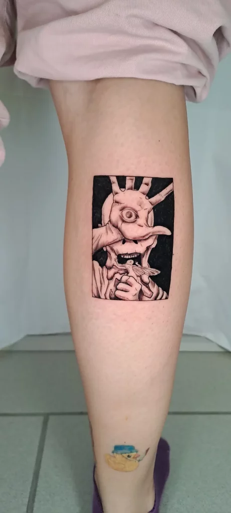 Tattoobild eines Alien im schwarzen Viereck, auf der Wade